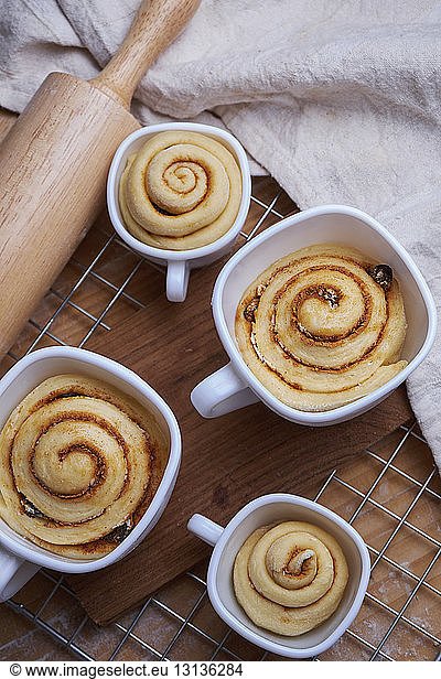 High angle view of cinnamon buns in cups on metal grate at kitchen counter