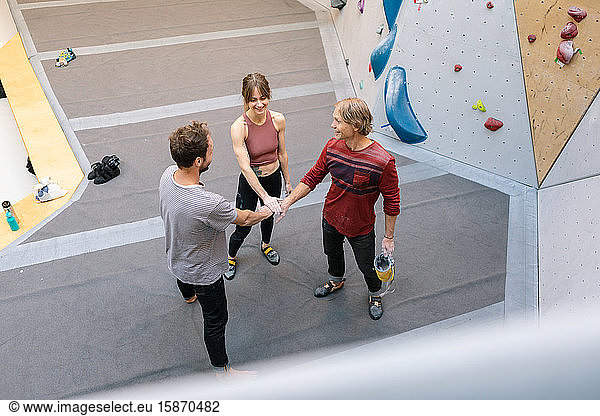 High angle view of coach and student stacking hands in unity at gym