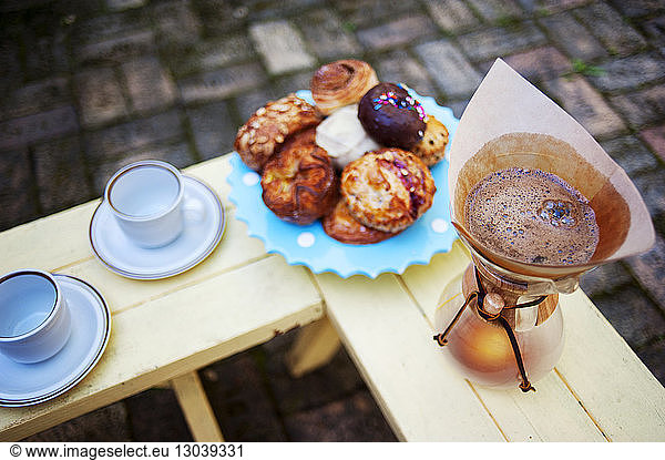 High angle view of coffee with desserts on wooden table at backyard