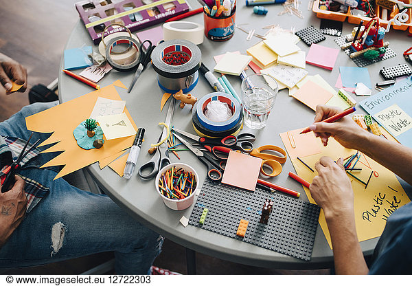 High angle view of colleagues working at table in creative office