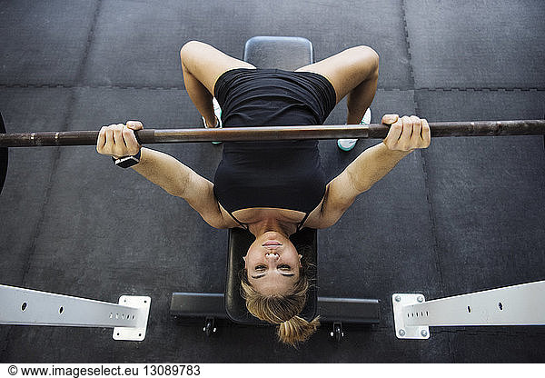 High angle view of confident athlete exercising with barbell in crossfit gym