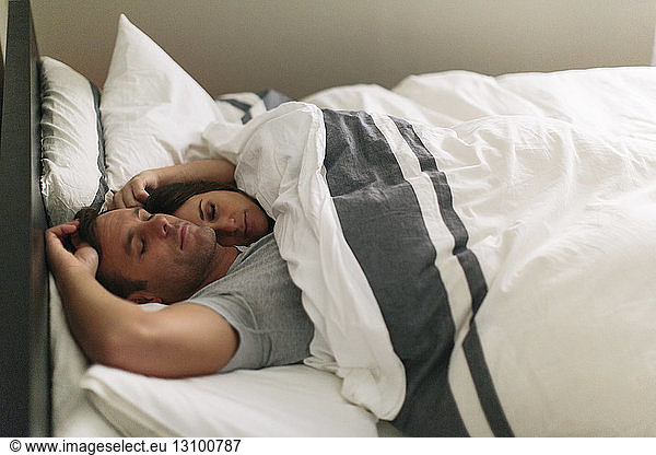 High angle view of couple sleeping in bed at home