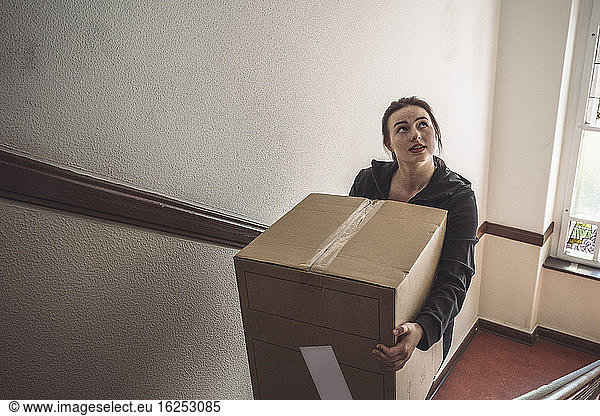 High angle view of delivery woman with cardboard box climbing steps