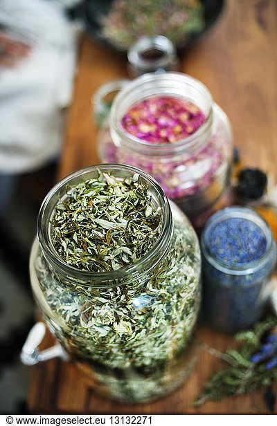 High angle view of dry herbs and petals in glass containers on table