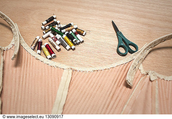 High angle view of fabric with colorful spools and scissors on table at workshop