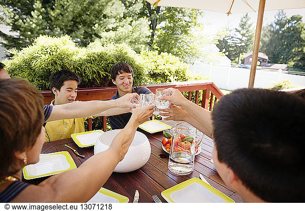 High angle view of family toasting drinking glasses while having food at porch