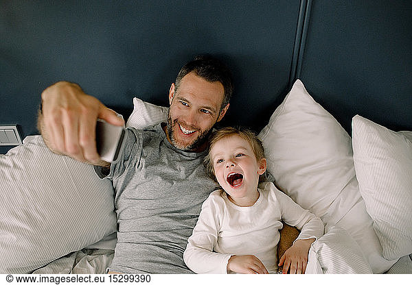 High angle view of father taking selfie with daughter on bed in hotel