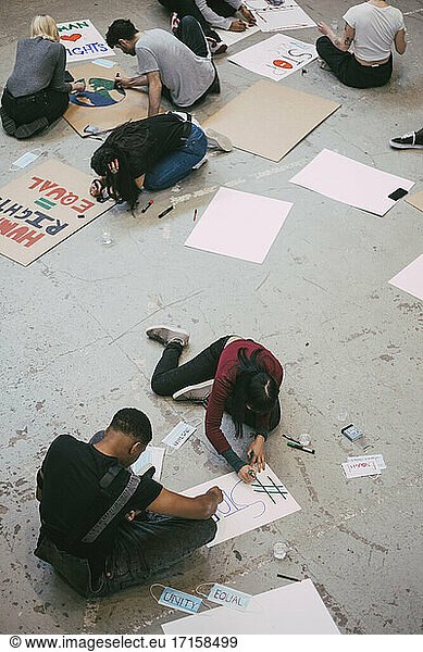 High angle view of female and male activist preparing signboard for social issues