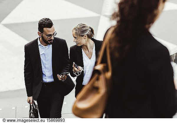 High angle view of female and male entrepreneurs talking while walking outdoors
