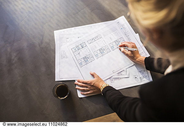 High angle view of female architect working on blueprint at table in office