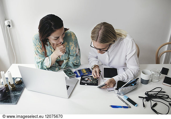High angle view of female engineers working on hard drive at table in home office