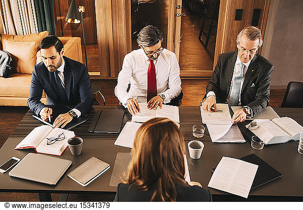 High angle view of female financial advisor planning with male lawyers in meeting at board room