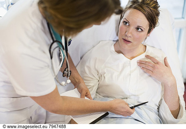 High angle view of female patient communicating with doctor in hospital ward