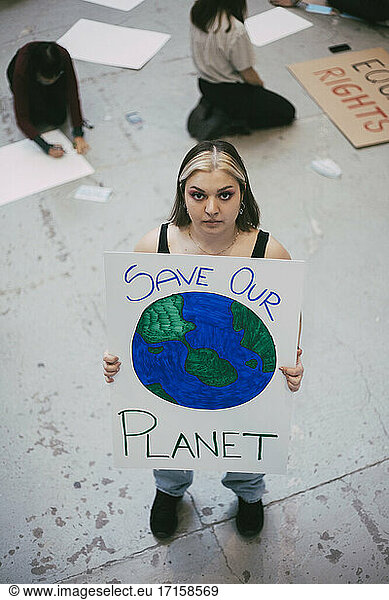 High angle view of female protector holding poster for environmental issues