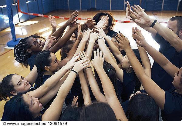 High angle view of female sports team huddling with arms raised