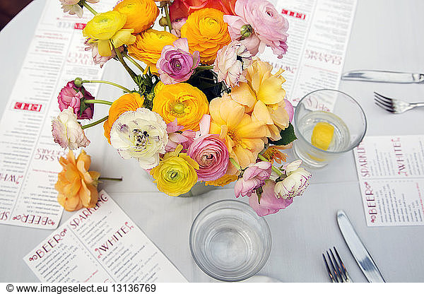 High angle view of flower vase with menus and water glasses on restaurant table