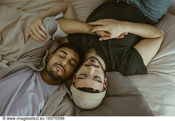 High angle view of gay couple sleeping on bed at home