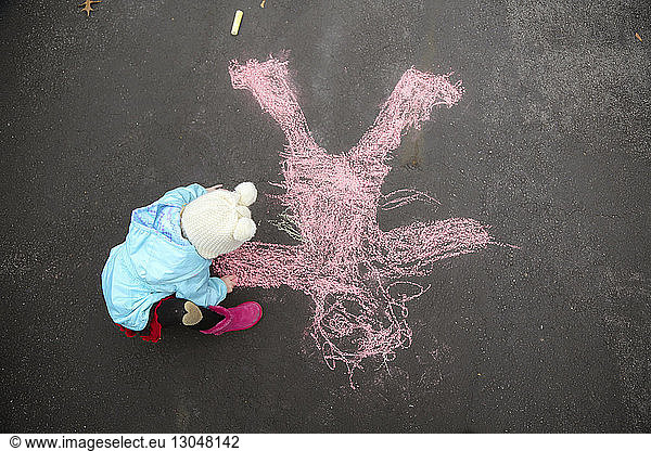 High angle view of girl drawing on asphalt