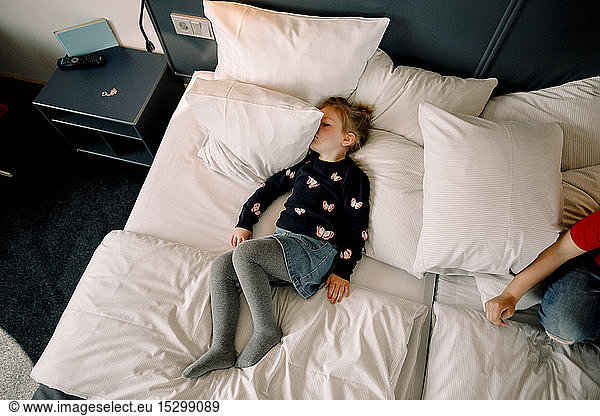 High angle view of girl lying on bed in hotel room