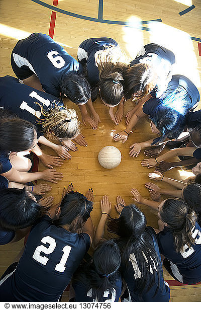 High angle view of girls volleyball team huddling on floor