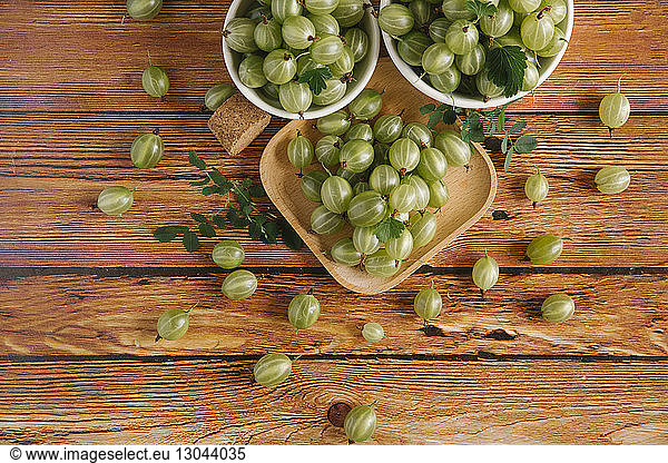 High angle view of gooseberries in containers on wooden table