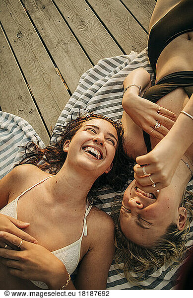 High angle view of happy female friends enjoying vacation while lying on jetty