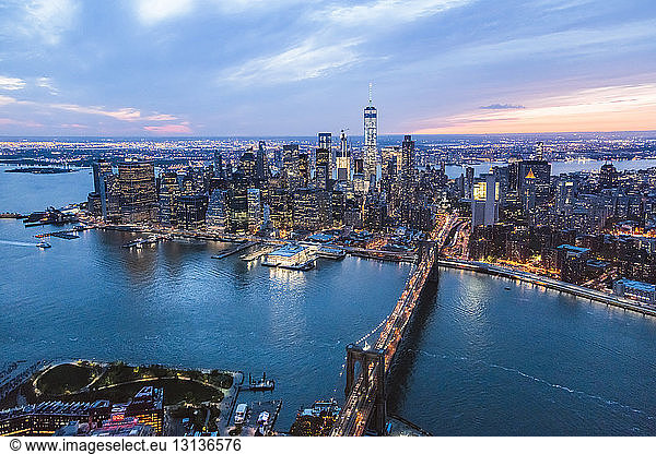 High angle view of illuminated Brooklyn Bridge over East River in city at dusk