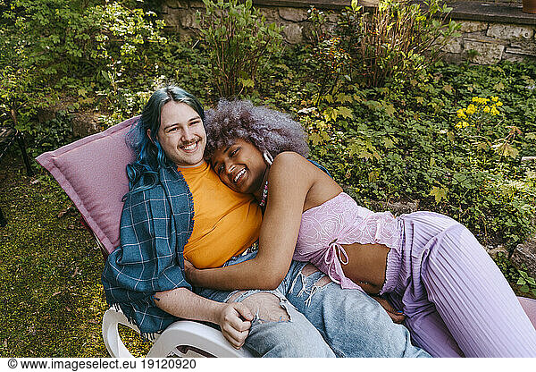 High angle view of LGBTQ friends relaxing on chair in back yard