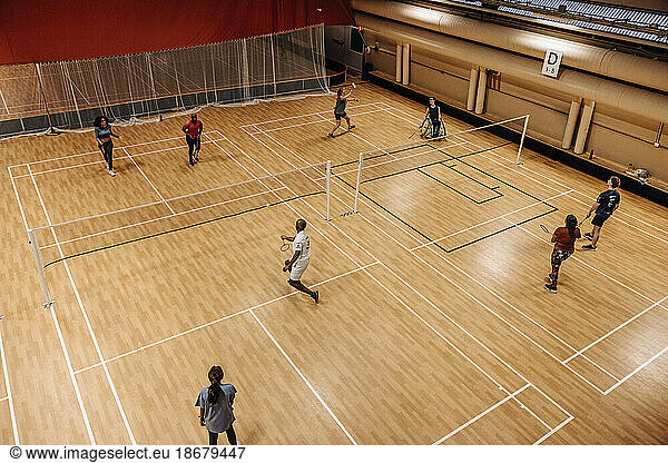 High angle view of male and female athletes playing badminton at sports court