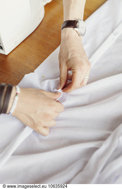 High angle view of male designer pinning white textile at table