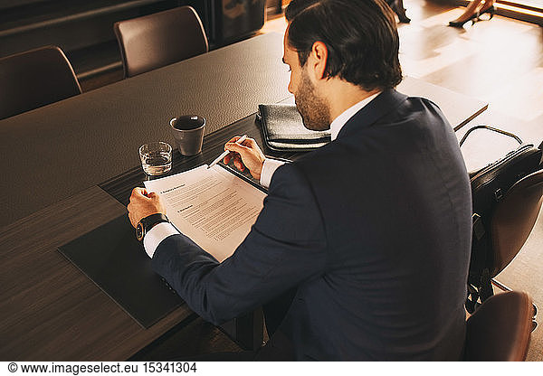 High angle view of male lawyer reviewing documents at table in law office