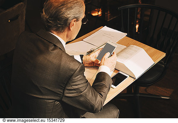 High angle view of male lawyer using smart phone while working at law office