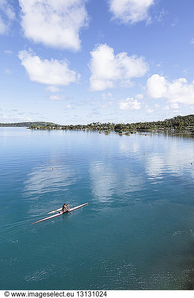 High angle view of man canoeing in lagoon of Bora Bora against sky