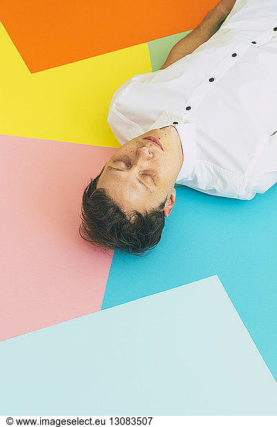 High angle view of man sleeping on colorful blank papers