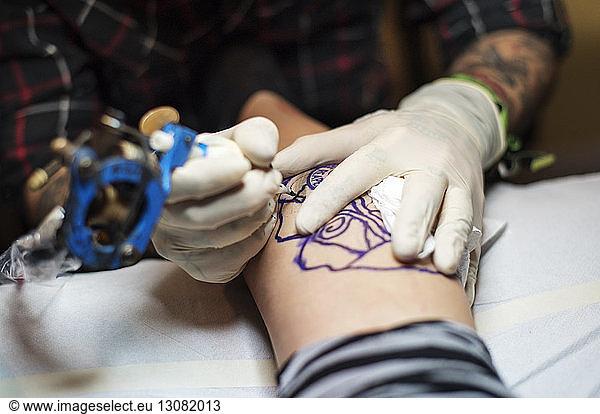 High angle view of man tattooing client at studio