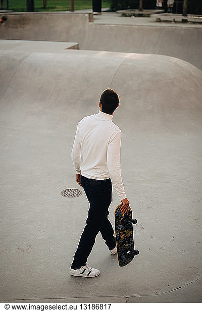High angle view of man with skateboard walking at park