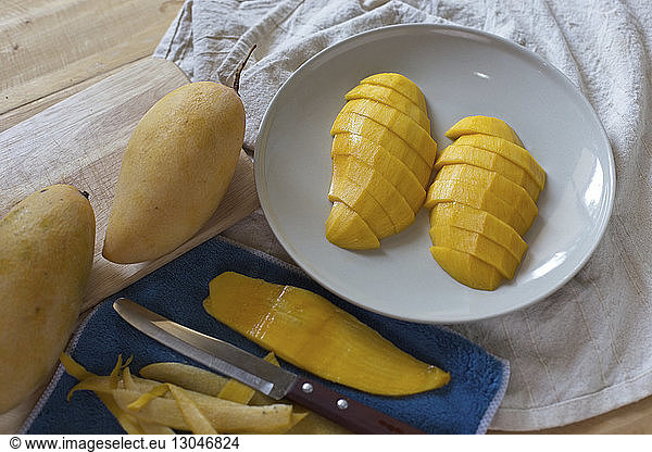 High angle view of mango slices in plate with napkin on table