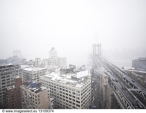 High angle view of Manhattan Bridge in city during snowfall
