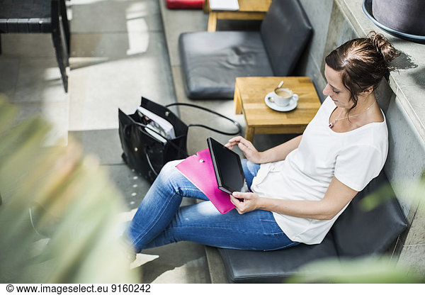 High angle view of mature woman using digital tablet in cafe