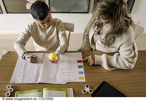 High angle view of mother teaching autistic son in living room