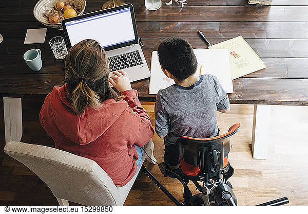 High angle view of mother with autistic son watching video on laptop while sitting at home