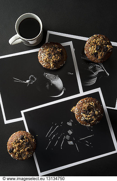 High angle view of muffins with coffee and photographs on table