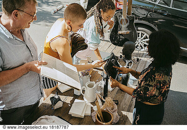 High angle view of owner processing online payment of female customer at flea market