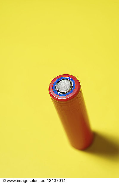 High angle view of red battery on yellow background