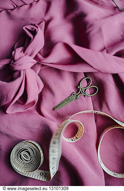 High angle view of scissors and tape measure on dress