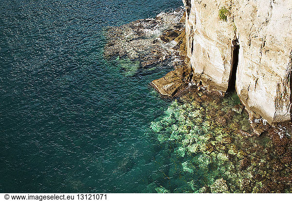High angle view of sea by rocky cliff
