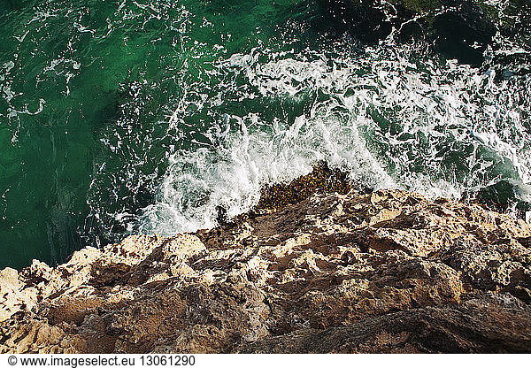 High angle view of sea waves splashing on rock formation