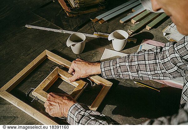High angle view of senior craftsman making wooden frame at workshop