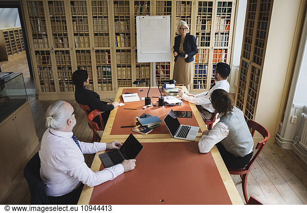 High angle view of senior lawyer giving presentation to coworkers in board room