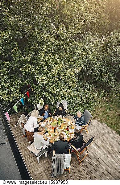 High angle view of senior woman serving friends sitting at dining table during garden party in back yard